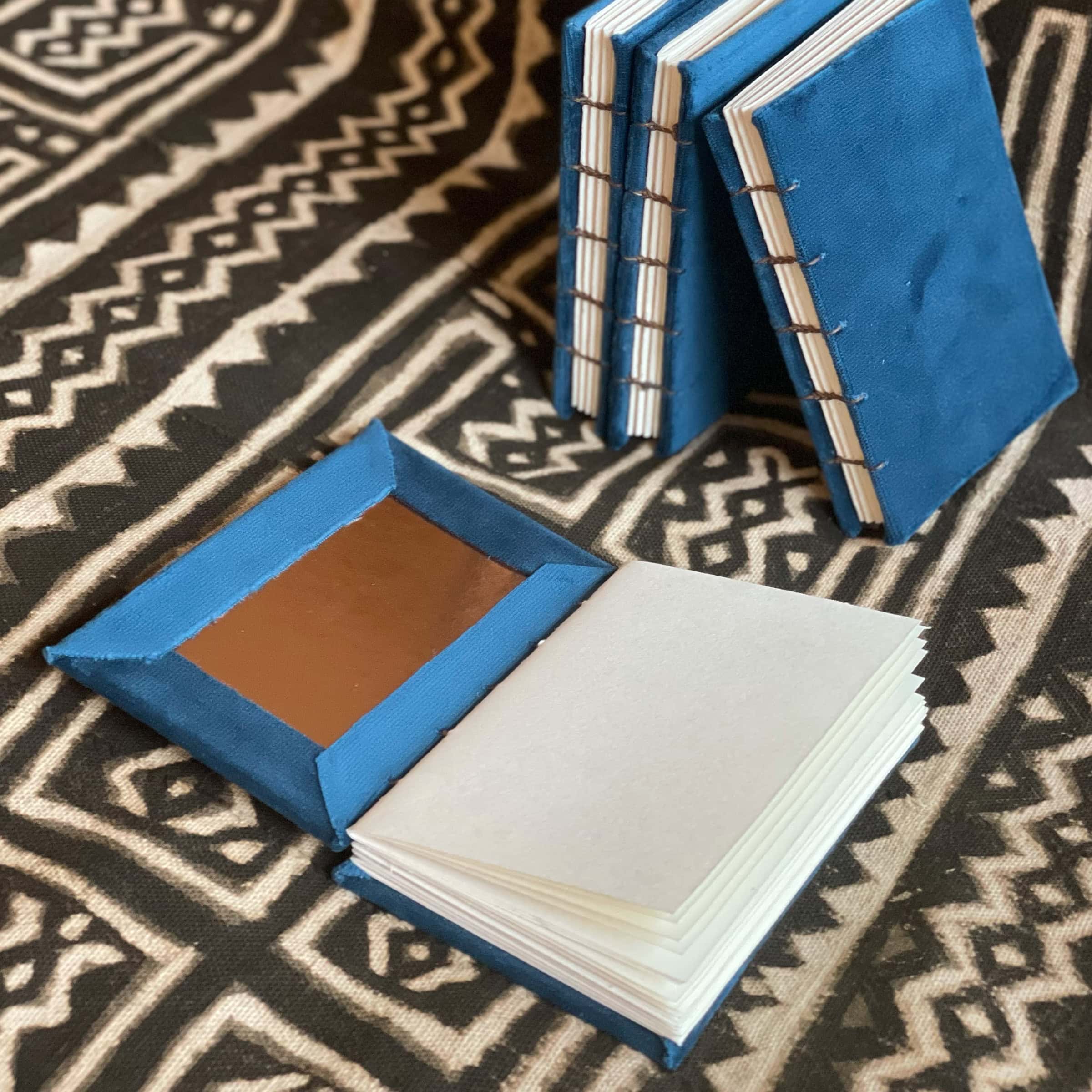 This is an image of handmade sketchbooks. This particular image features one book laying open flat on a surface to show the inside cover